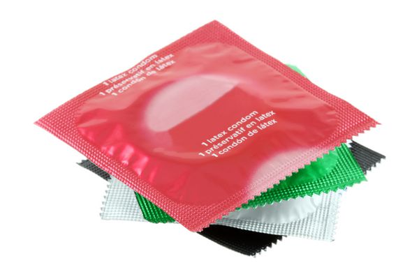 بسته های رنگارنگ انواع مختلف کاندوم جدا شده روی سفید
