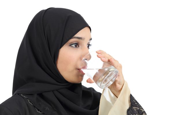 زن عرب در حال نوشیدن آب از یک لیوان جدا شده در زمینه سفید