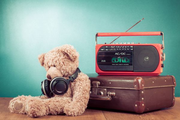 اسباب بازی رترو خرس عروسکی و ضبط رادیویی روی چمدان در پس زمینه نعناع جلو