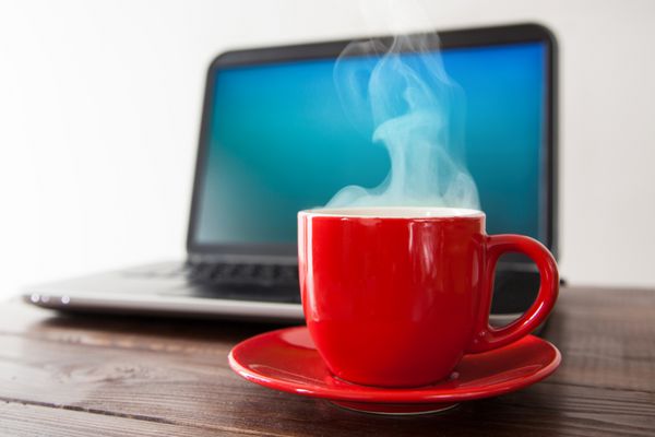 لپ تاپ و یک فنجان قهوه روی میز