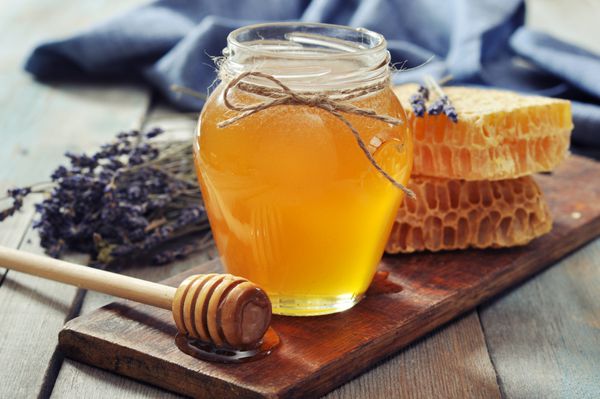 عسل در شیشه با عسل در پس زمینه چوبی قدیمی