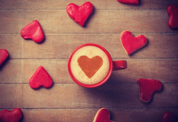 فنجان قهوه با نماد قلب و آب نبات در اطراف