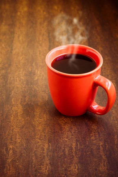 فنجان با قهوه سیاه روی پس زمینه چوبی