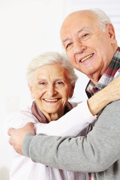 زوج سالمند شادی که با هم می رقصند و لبخند می زنند