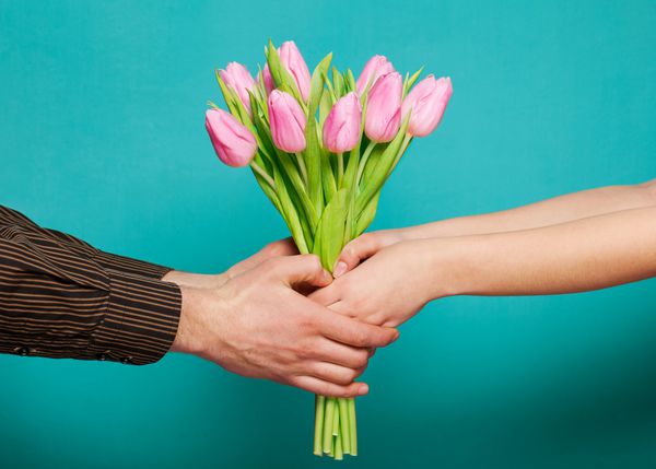 زوج عاشق دسته گل لاله در پس زمینه آبی در دست دارند مفهوم روز