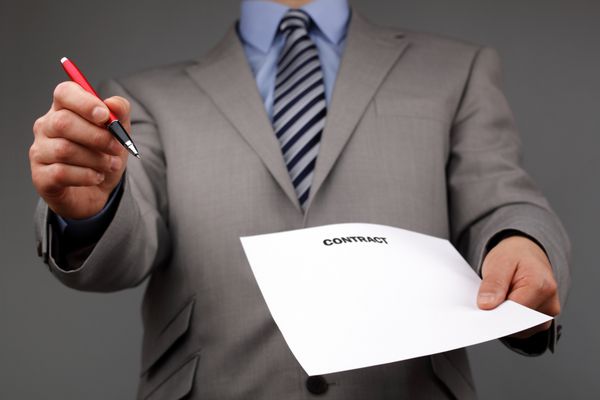 دست بازرگانان که یک خودکار در دست دارند و درخواست امضای قرارداد یا سند می کنند