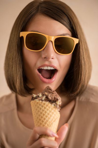 زن بستنی در حال آواز خواندن در مخروط مانند میکروفون شاد شاد و شاد مدل زن جوان ناز در حال خوردن قیفی بستنی