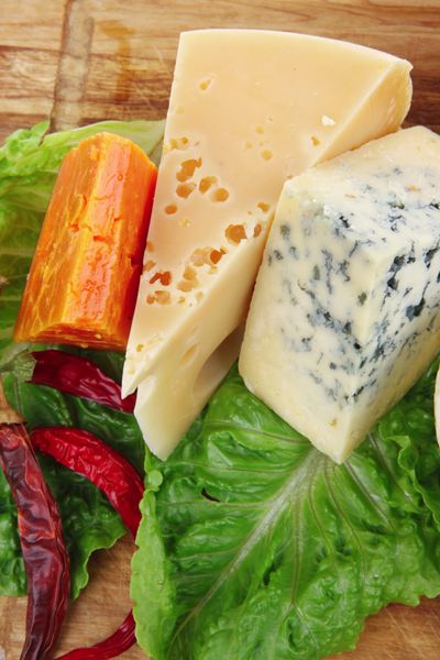 پنیر فتا نرم با پنیرهای خوشمزه کهنه شده روی بشقاب چوبی برش با نان گوجه فرنگی و روغن زیتون جدا شده روی پس زمینه سفید