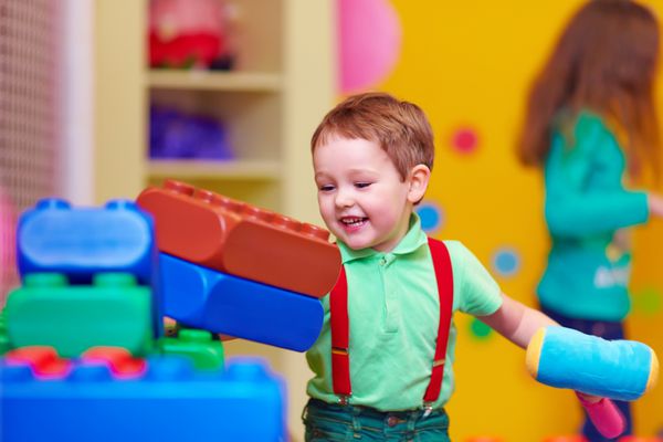بچه شاد در حال شکستن اسباب بازی ها در مهدکودک
