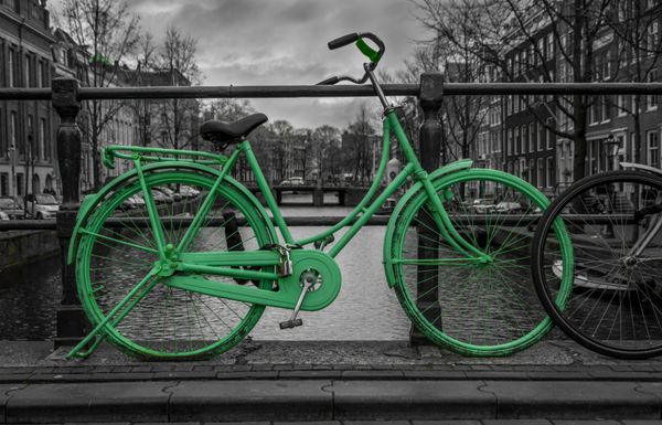 دوچرخه سبز جدا شده روی سیاه و سفید بر فراز کانال آمستردام آسمان بسیار بد خلق در پس زمینه