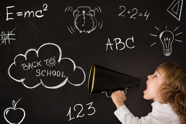 فریاد کودک مدرسه ای از طریق مگافون قدیمی در برابر تخته سیاه مفهوم آموزش بازگشت به مدرسه