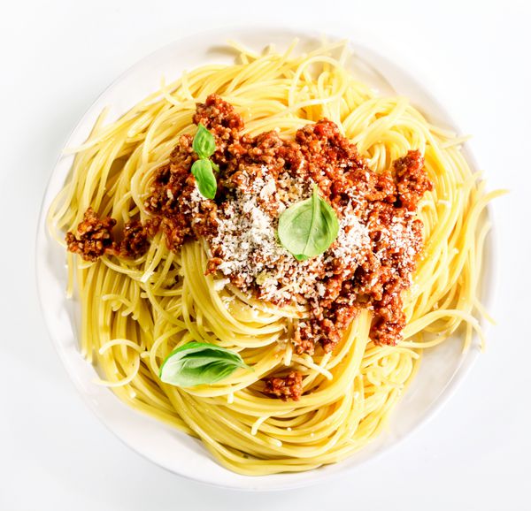 سرو اسپاگتی بولونیز ایتالیایی با گوشت چرخ کرده پنیر پارمزان و برگ های ریحان تازه برای غذاهای سنتی مدیترانه ای خوشمزه نمای بالای سر به رنگ سفید
