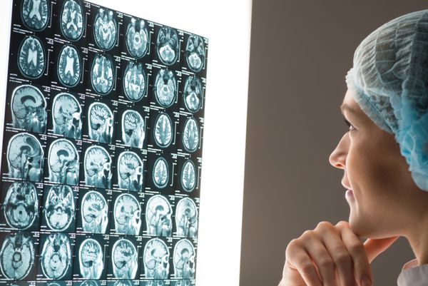 دکتر زن که به تصویر اشعه ایکس متصل به صفحه نمایش درخشان نگاه می کند