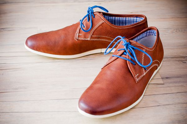 یک جفت کفش چرمی مردانه با ls pld رنگارنگ روی کف چوبی