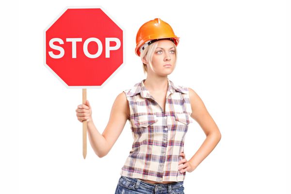 کارگر ساختمانی زن که علامت توقف جدا شده در پس زمینه سفید را در دست دارد