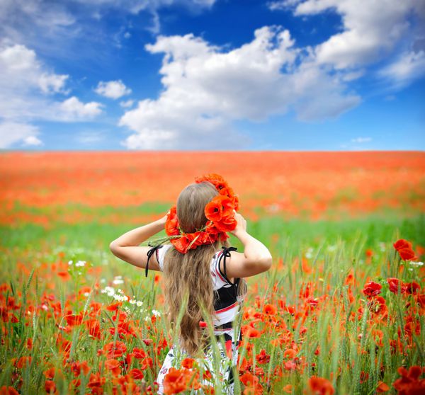 زن جوان زیبا در مزرعه خشخاش قرمز روشن