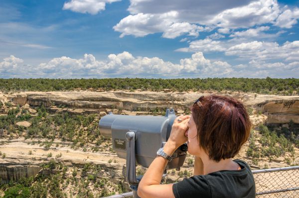 زن جوان از طریق تلسکوپ به مناظر نگاه می کند