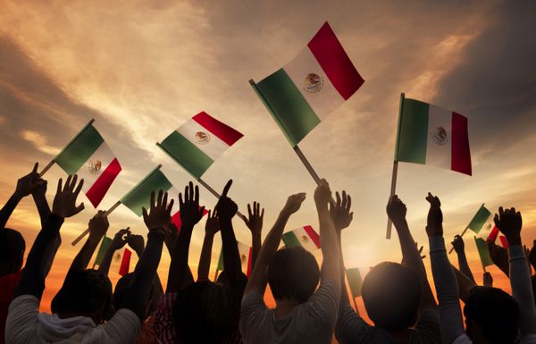 گروهی از مردم که پرچم های ملی مکزیک را در دست دارند