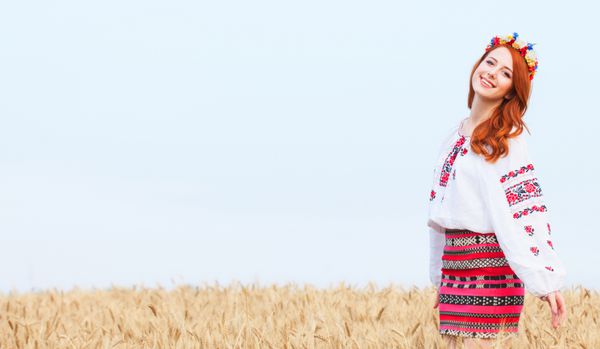 دختر مو قرمز با لباس ملی اوکراین در مزرعه گندم