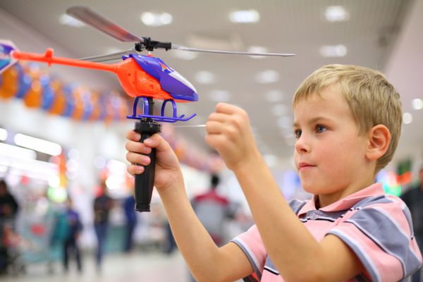 پسر در مغازه با هلیکوپتر اسباب بازی