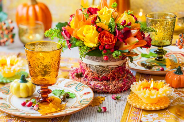 چیدمان میز جشن با سبد گل های پاییزی شمع و کدو تنبل