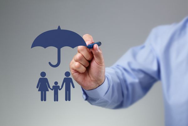 دست تاجری که یک چتر بالای یک مفهوم خانوادگی برای حفاظت امنیت امور مالی و بیمه می کشد