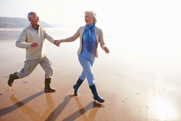 زوج سالخورده ای که در امتداد ساحل زمستانی می دوند