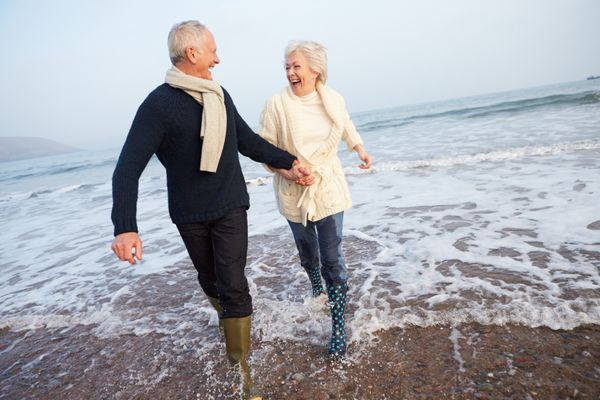 زوج سالخورده ای که در امتداد ساحل زمستانی قدم می زنند