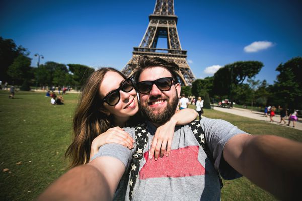 زوج عاشقانه در حال سلفی گرفتن مقابل برج ایفل در حال سفر در پاریس فرانسه دانش آموزان خندان شاد از تعطیلات خود در اروپا لذت می برند