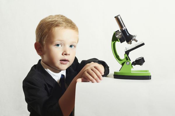 دانشمند کوچولو پرتره مد پسر کوچولو با کراوات کودک خنده دار پسر مدرسه ای که با میکروسکوپ کار می کند بچه باهوش علم