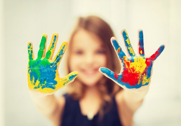 آموزش مدرسه هنر و مفهوم نقاشی - دختر دانش آموز کوچکی که دست های نقاشی شده را نشان می دهد