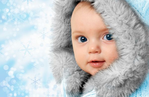 دختر بچه زیبا روی پس زمینه پوسته برف که یک کت خز زمستانی پوشیده است