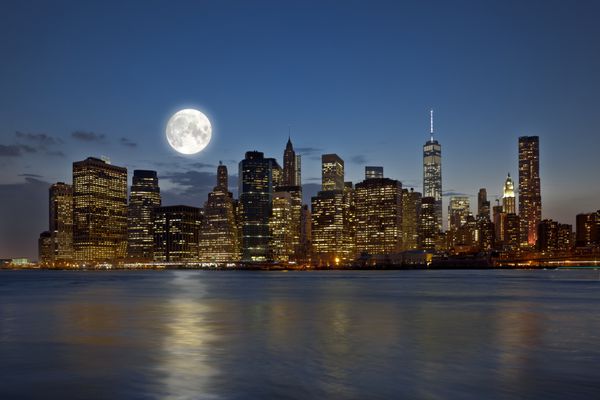 نمای پانوراما نیویورک سیتی منهتن افق مرکز شهر در شب با آسمان خراش ها و ماه کامل روشن