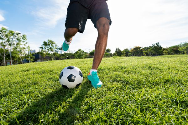 پاهای بازیکن فوتبال که به توپ لگد می زند
