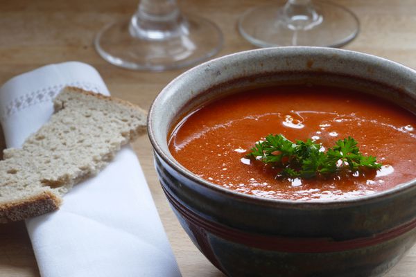 جزئیات یک سوپ سبزیجات قرمز گوجه فرنگی هویج یا کدو تنبل در یک کاسه سفالی با نان