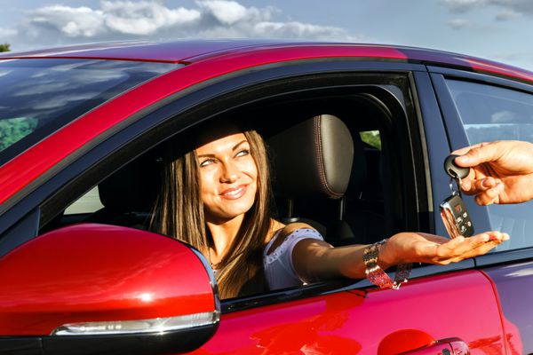 زن جوانی که کلید ماشین قرمز لوکس جدید را می گیرد