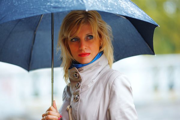 دختری با چتر سیاه زیر باران هزینه می کند