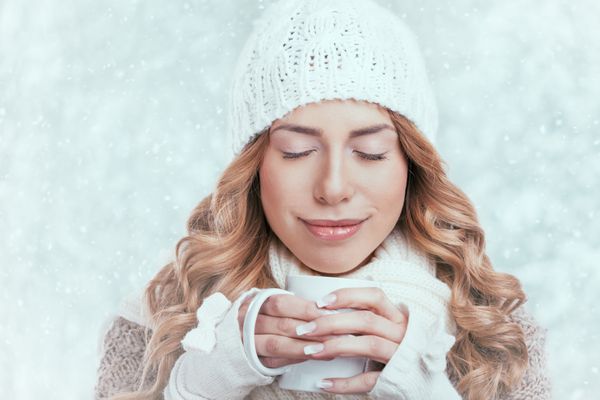 زن در حال لذت بردن از لیوان بزرگ نوشیدنی در طول روز سرد