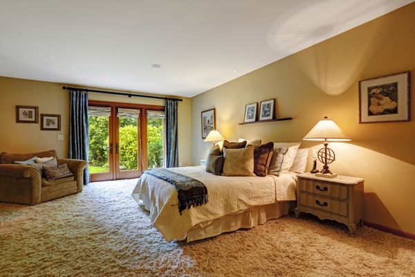 داخلی اتاق خواب مستر با خروجی به حیاط خلوت فرش نرم و تخت ملکه با بالش فضای داخلی راحتی را ایجاد می کند
