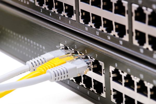 نمای جزئی سوئیچ شبکه LAN با سه کابل اترنت وصل شده نمای نزدیک با دف کم عمق جدا شده در زمینه سفید