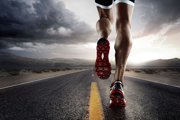 پس زمینه ورزشی پاهای دونده در حال دویدن در نزدیکی جاده روی کفش