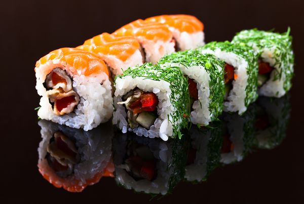 سوشی ژاپنی اشتها آور در پس زمینه انعکاسی سیاه