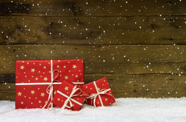 هدایای کریسمس قرمز در زمینه چوبی با برف