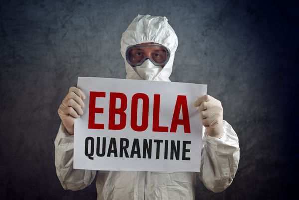 تابلوی قرنطینه ابولا توسط کارمند مراقبت های بهداشتی با لباس محافظ دستکش ماسک و عینک محافظت می شود