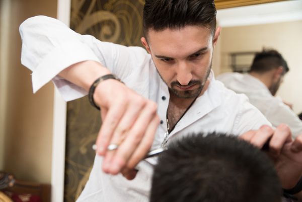 دست های آرایشگر حرفه ای - آرایشگر جوان خوش تیپ که یک مدل موی جدید به مشتری مرد در سالن ارائه می دهد