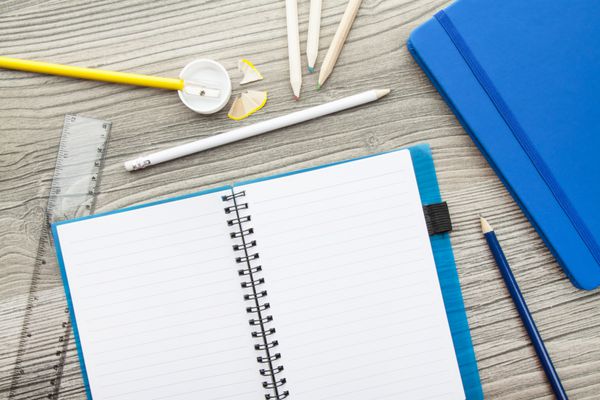 مجموعه لوازم اداری - تراش مداد خودکار دفترچه یادداشت و خط کش - روی میز چوبی قهوه ای