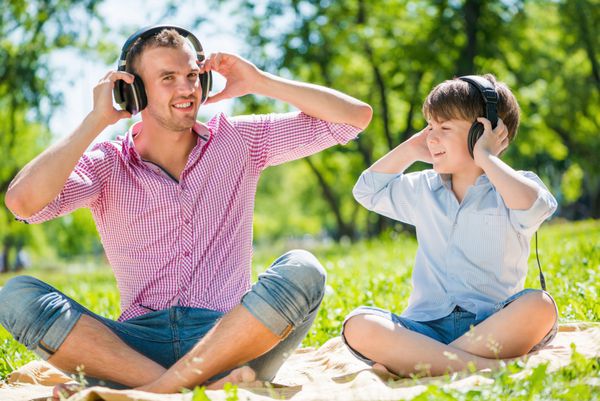پدر و بچه در پارک تابستانی در حال لذت بردن از موسیقی