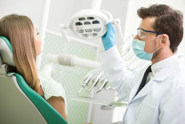 دندانپزشک در حال درمان یک بیمار زن در مطب دندانپزشکی است