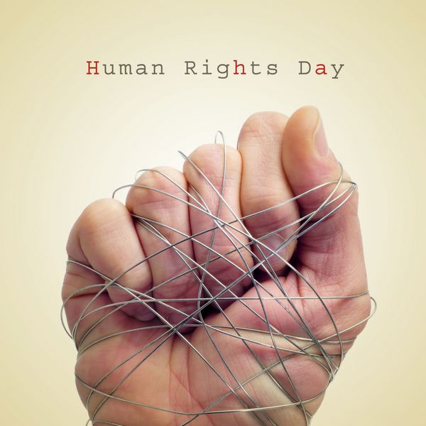 مردی که دستی با سیم بسته شده و متن روز حقوق بشر در زمینه بژ