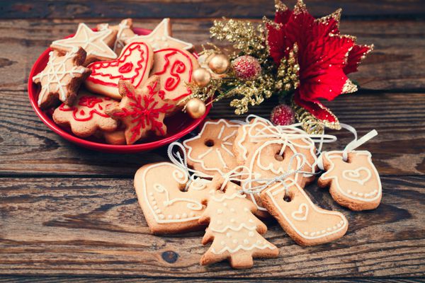 شیرینی های دست ساز کریسمس روی پس زمینه چوبی شیرینی زنجفیلی گوزن شمالی و تزئین کریسمس درخت کریسمس
